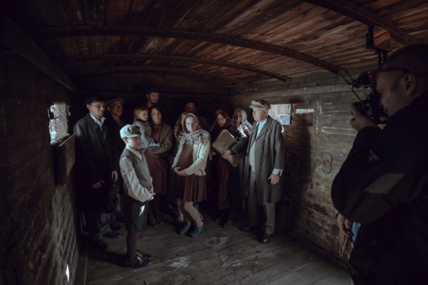 Kulisy powstawania filmu „Położna z Auschwitz”. Operator kręci grupę w baraku.