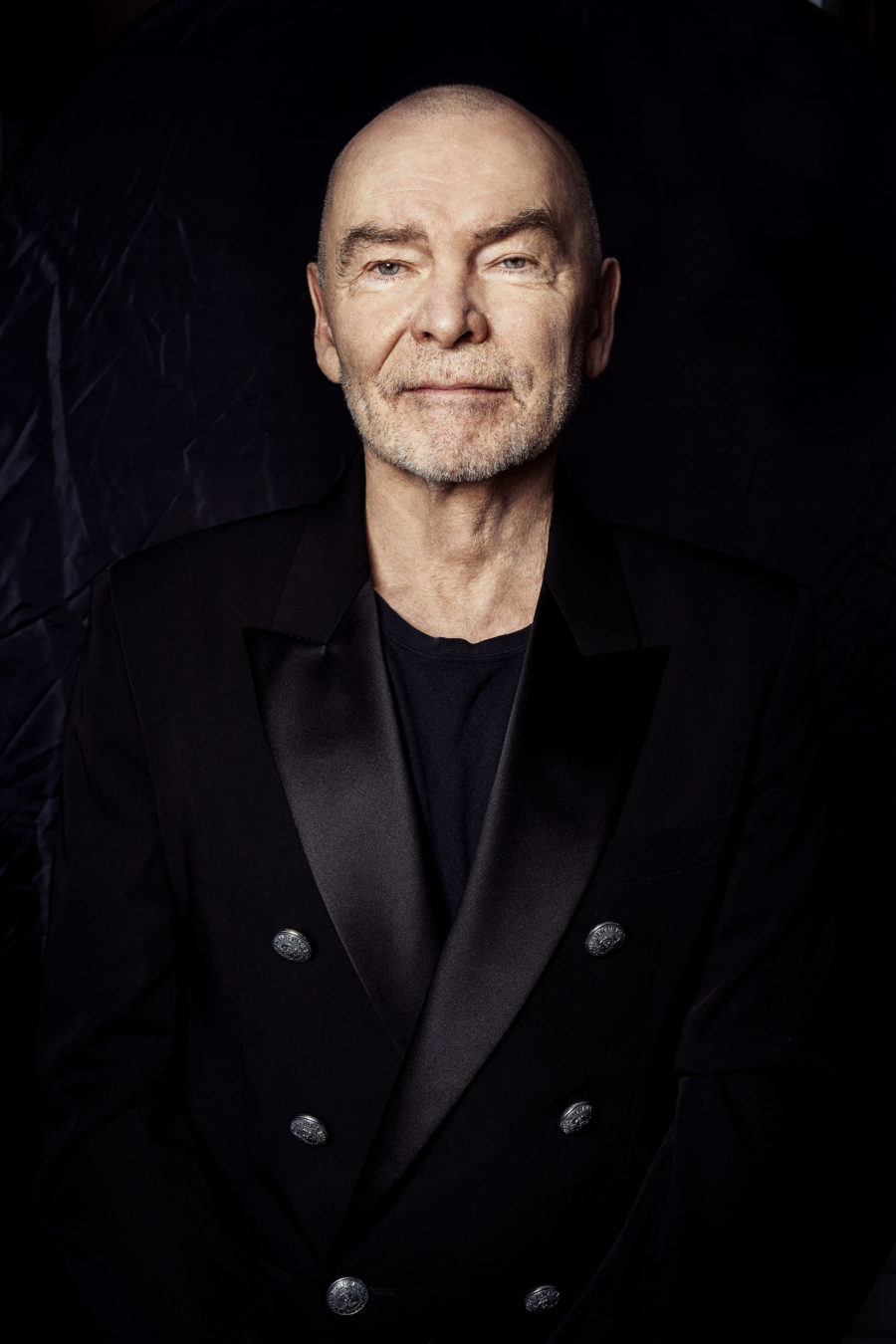 Portret łysego mężczyzny na tle białej ściany.