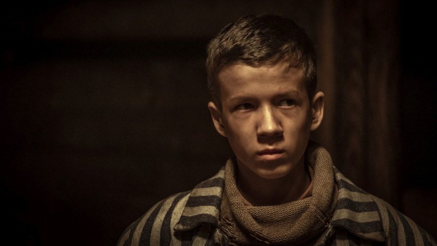 Kadr z filmu, chłopiec w ubraniu więziennym patrzy się poważnie na coś nieujętego w kadrze.