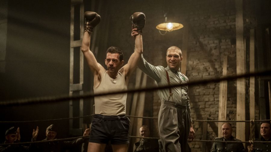 Kadr z filmu, sędzia unosi rękę boksera na ringu, ukazuje w ten sposób zwycięzcę walki. Bokser ma uniesione obie ręce do góry w geście zwycięstwa.