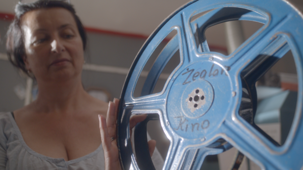 Kobieta z pustą szpulą filmową z napisem "Kino Żeglarz".